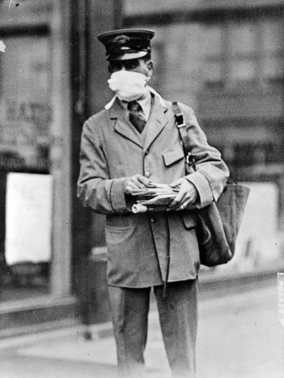 pandemics-Letter carrier in New York wearing mask for protection against influenza
