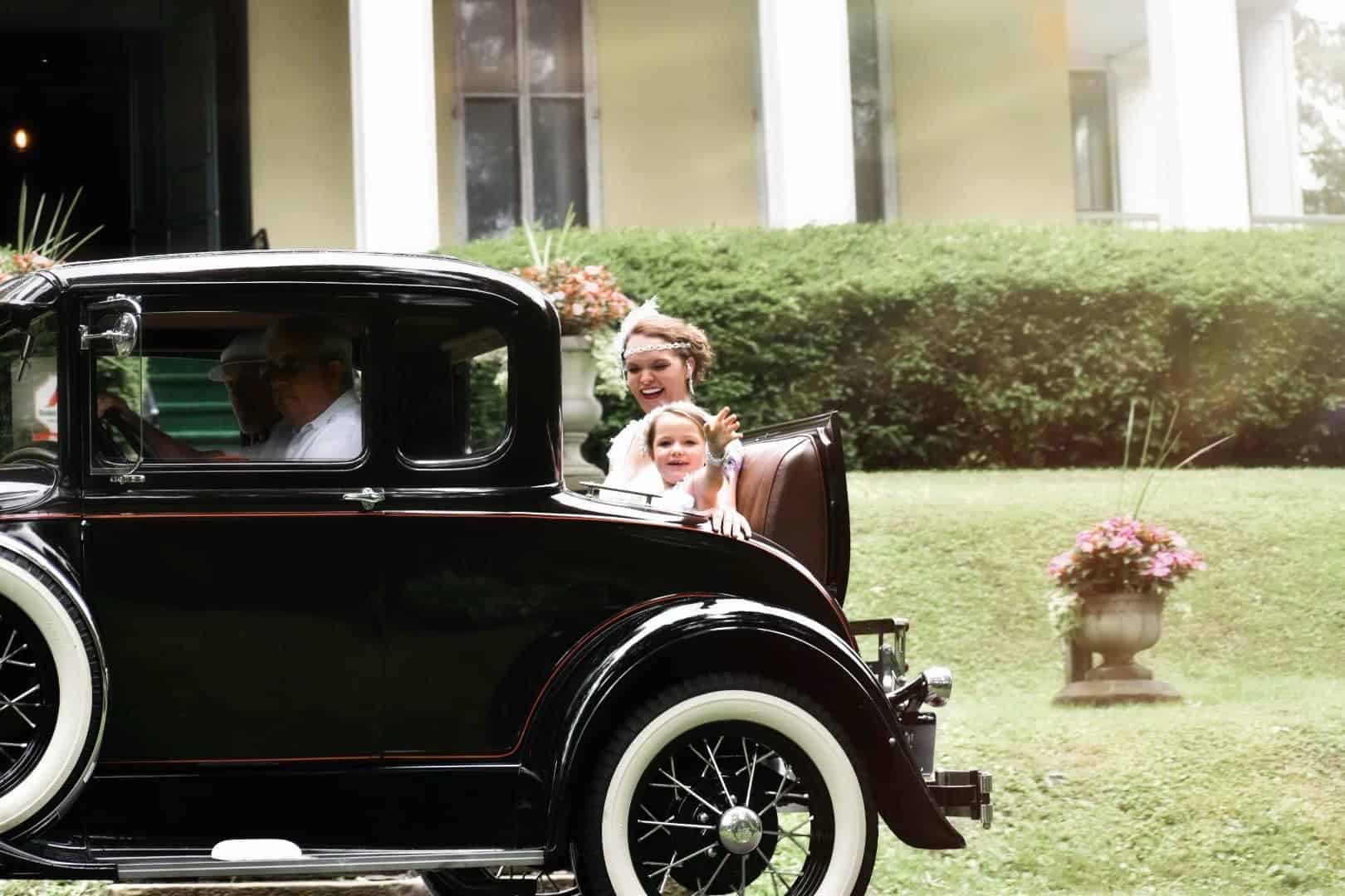 Photo of a car with two people on it, a baby is waving